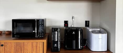 Una kitchenette con microondas, cafetera y tostadora sobre una encimera de madera.