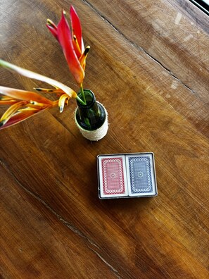 Superficie de madera con una botella verde pequeña y una flor roja.