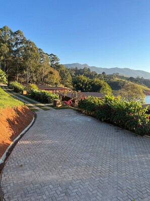 Un sendero pavimentado que lleva a un edificio con vistas a un lago y montañas a lo lejos.