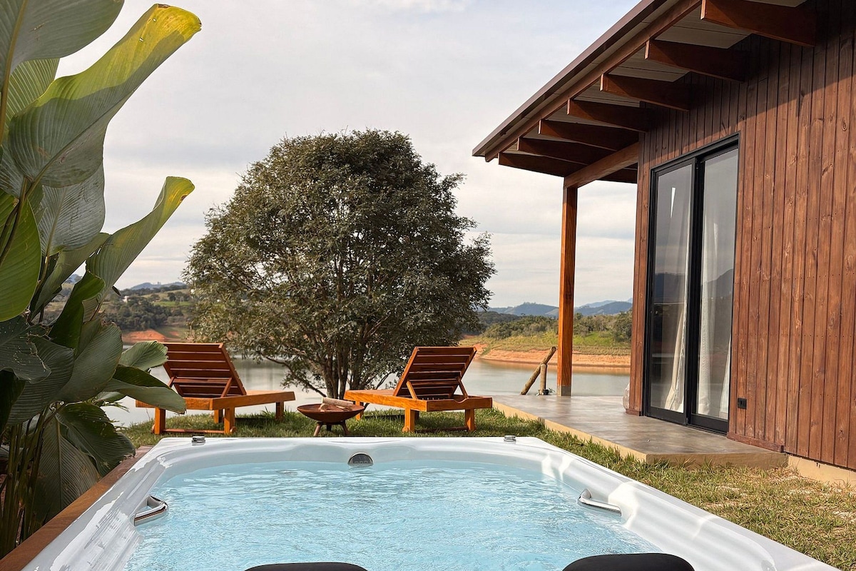 Un jacuzzi con dos sillones reclinables, una terraza de madera y vistas a un árbol y al paisaje.