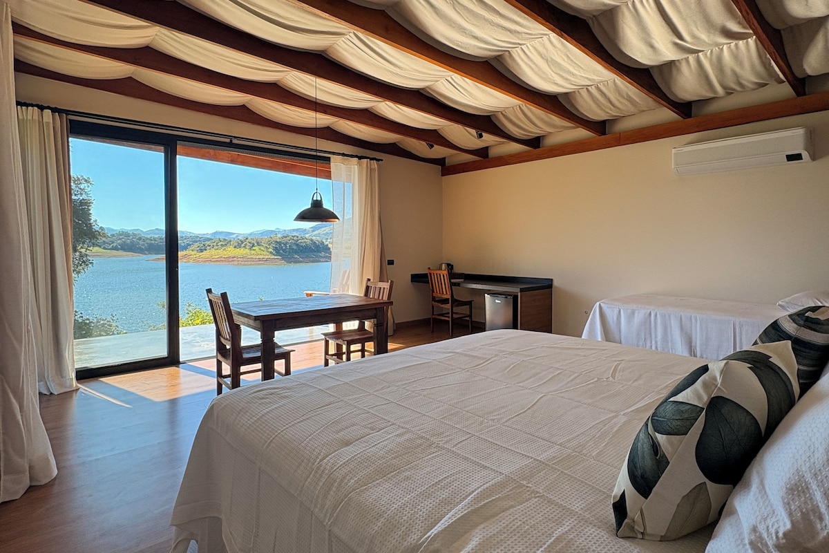 Un dormitorio con una cama grande, un escritorio y vista a un lago.