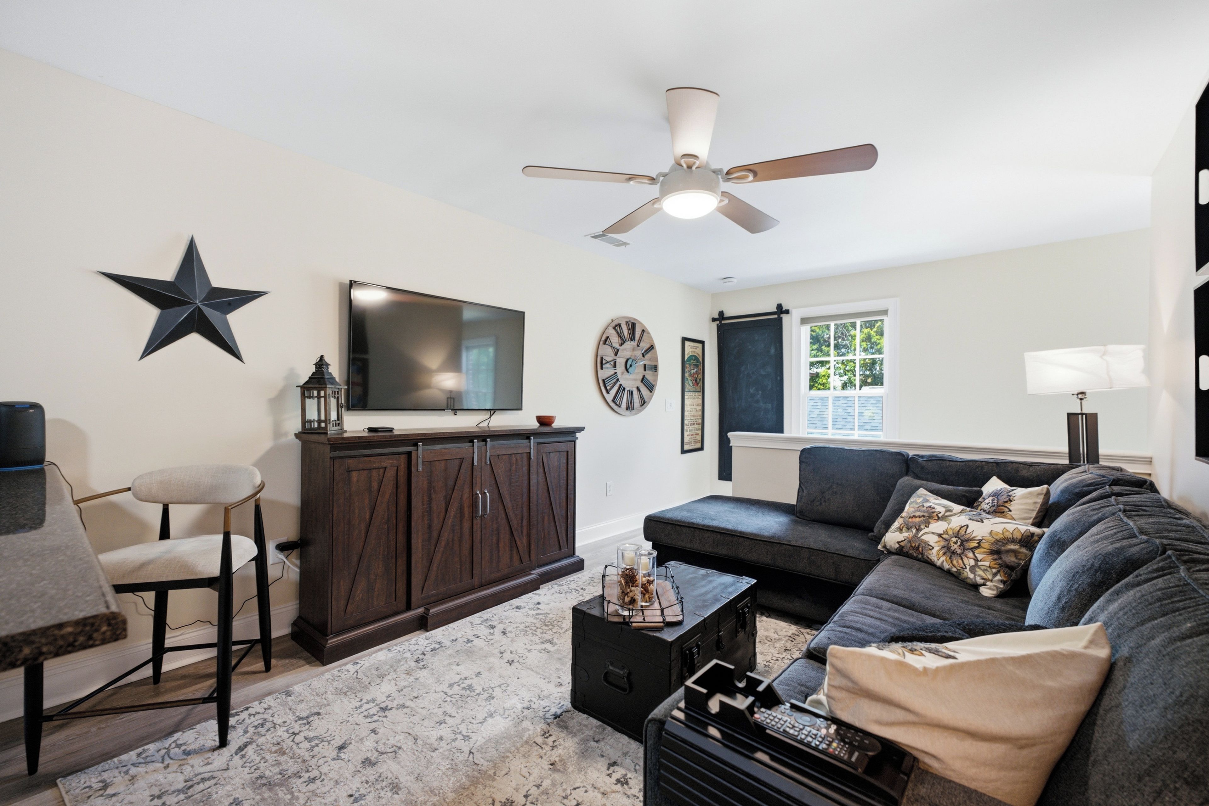 A living room with a dark wooden cabinet, a television, a star decoration, a clock, and a ceiling fan.