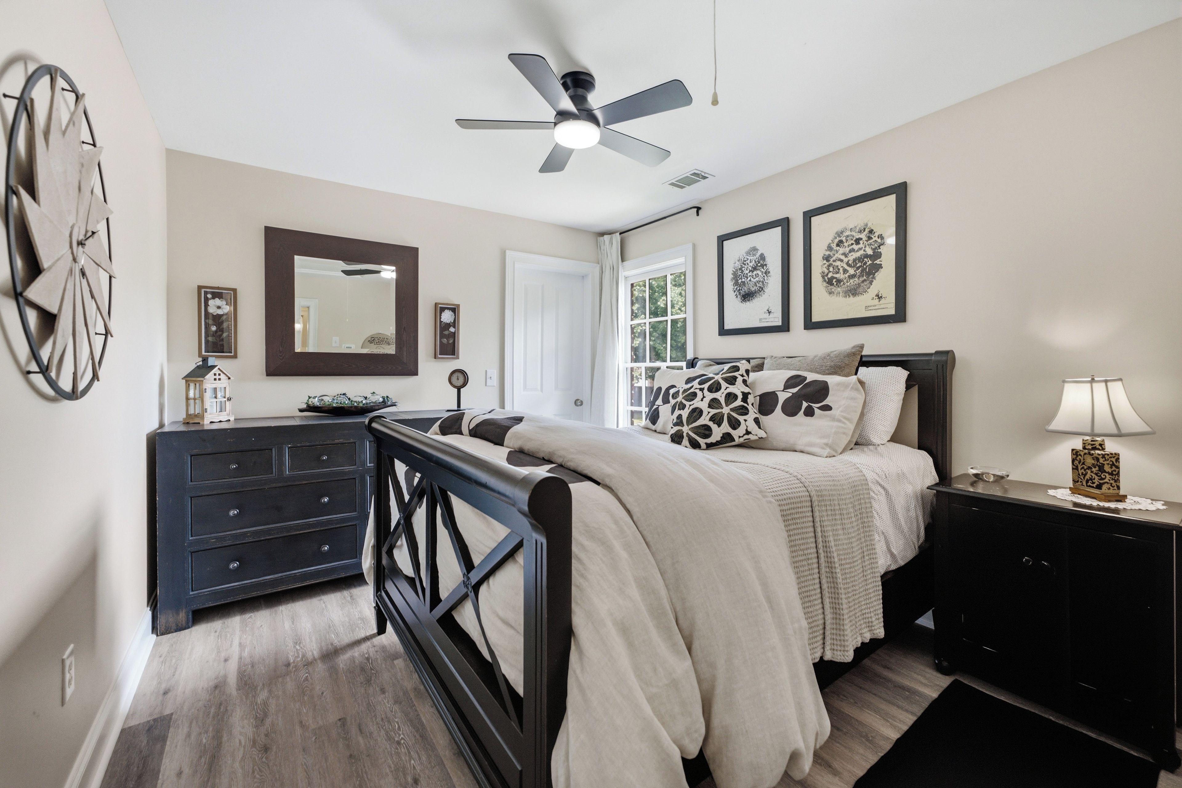 A bedroom with a bed, dresser, and a ceiling fan.