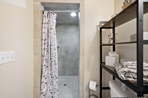 Une salle de bain avec une douche, des toilettes, une étagère avec des serviettes et un élément décoratif en forme d’étoile.