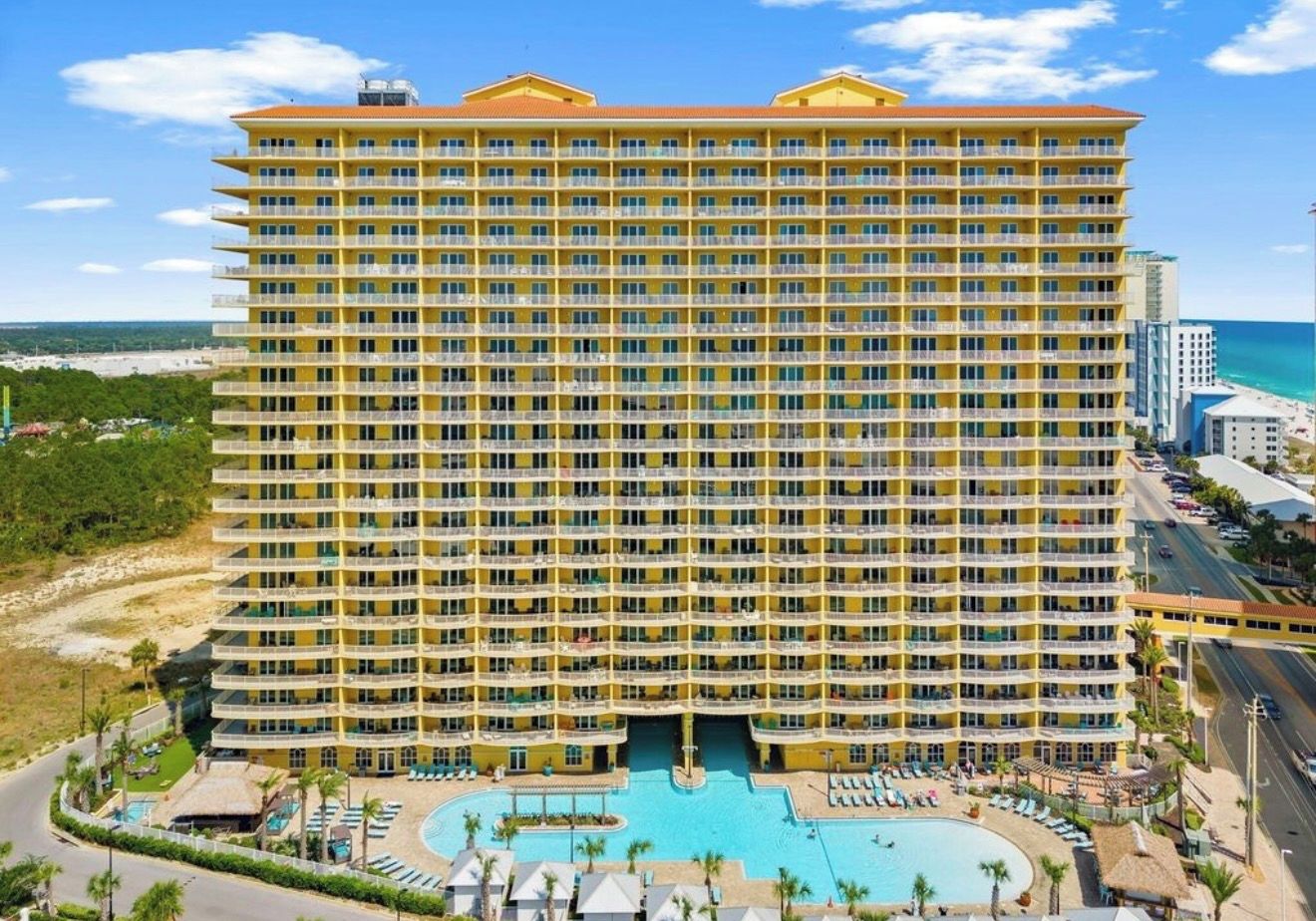 A multi-story hotel with a central courtyard and a pool.