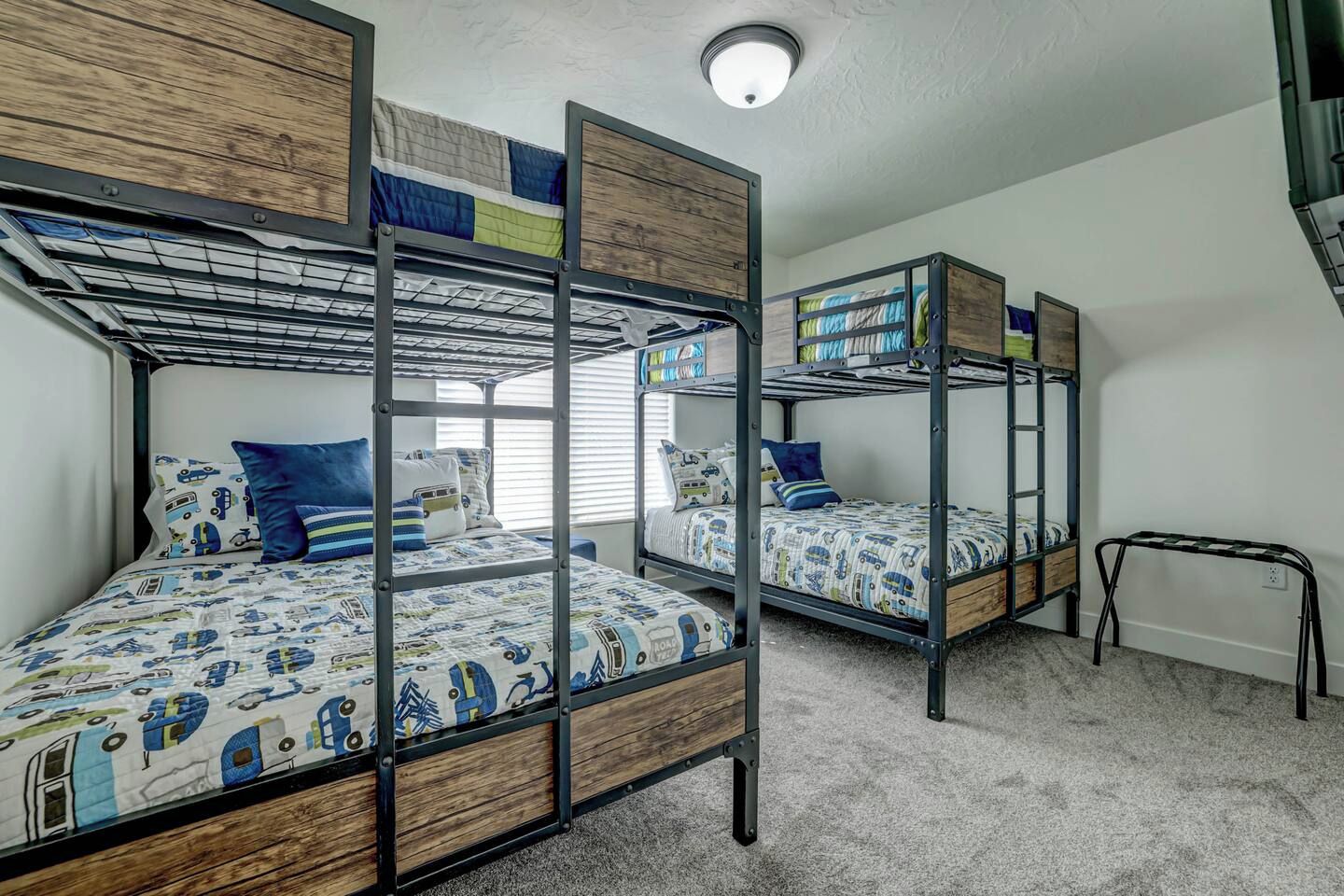 Une chambre avec des lits superposés, chacun doté d’une structure en bois et de draps à motifs.