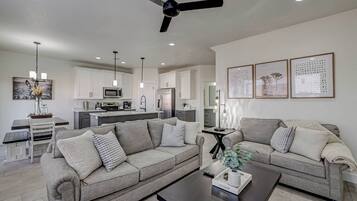 A modern living room with two sofas, a coffee table, and a dining area with a table and chairs.