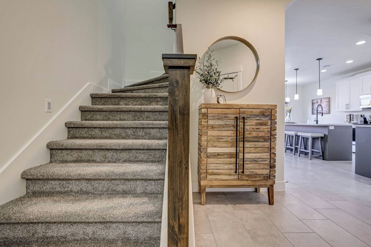 Eine Treppe mit Teppichstufen führt zu einer Zwischenebene, einem Holzkasten mit Schubladen und einem Küchenbereich mit einer Bar.