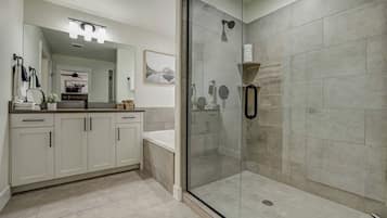 A modern bathroom with a glass-enclosed shower, a vanity with a mirror, and a sink.