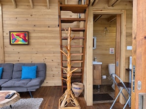 A wooden interior with a sofa, a decorative wooden sculpture, and a bathroom visible through an open door. - Cómoda Cabaña en Marinilla con jacuzzi (Marinilla)