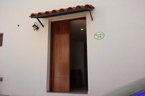 Une porte en bois avec un cadre en métal, un petit auvent au-dessus de la porte et une enseigne sur le mur à droite, sur laquelle on peut lire : « CASA AGAVERA LIVING ».