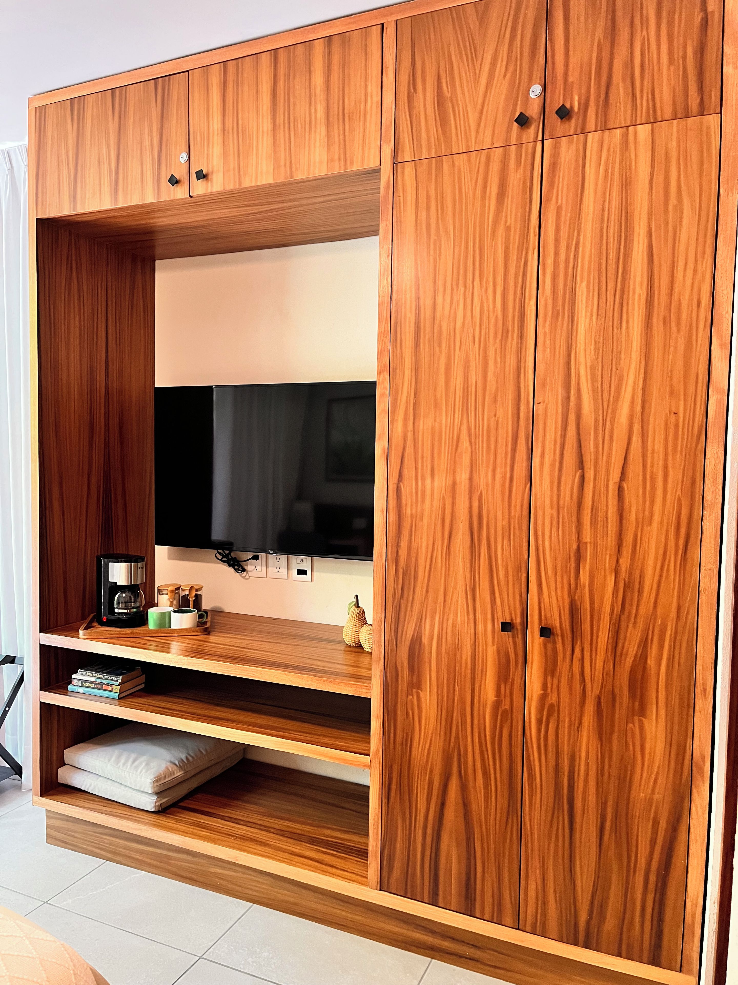 Une armoire en bois équipée d’un téléviseur à écran plat, d’étagères et d’une machine à café.