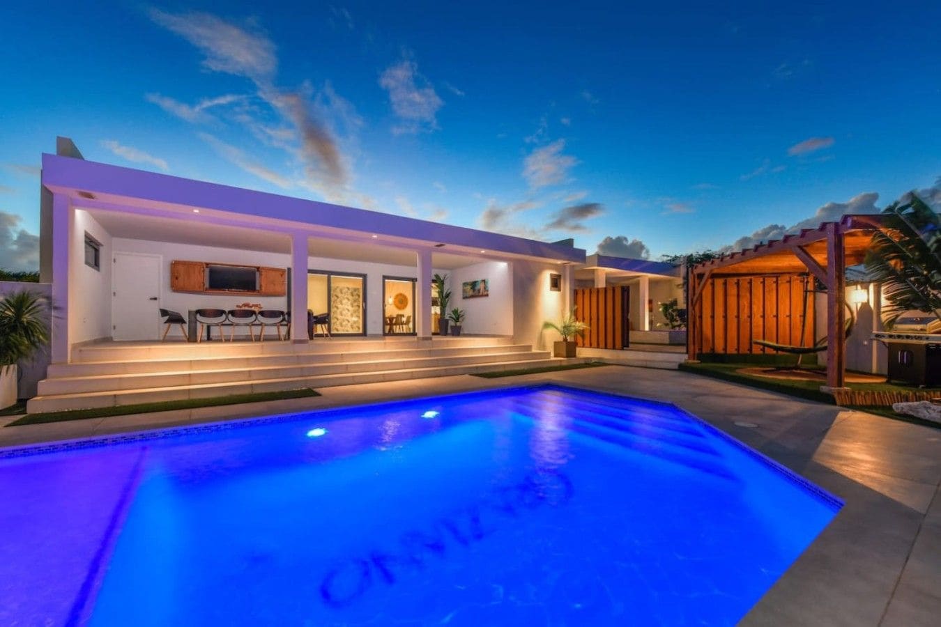 A modern house with a swimming pool, outdoor seating, and a covered patio area.