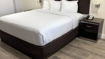 A hotel room with a large bed, a bedside table with a phone, and a wall-mounted light.