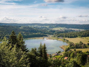 A lake surrounded by forested hills and a small settlement with houses.