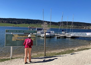 A person standing by a signboard with a map, near a marina with boats docked.