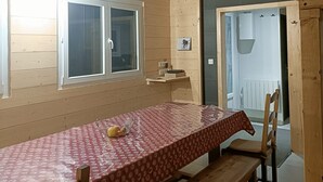 Uma área de refeições com mesa e bancos, uma janela e uma porta que dá para outro cômodo.
