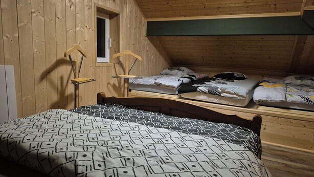 Quarto com cama, janela e teto de madeira.