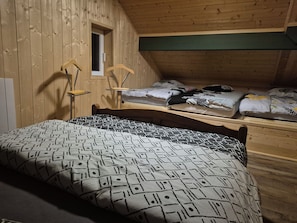 A room with a bed, a window, and a wooden ceiling.