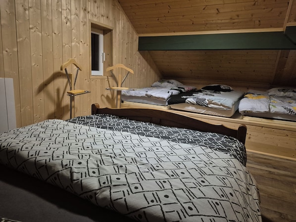 A room with a bed, a window, and a wooden ceiling.