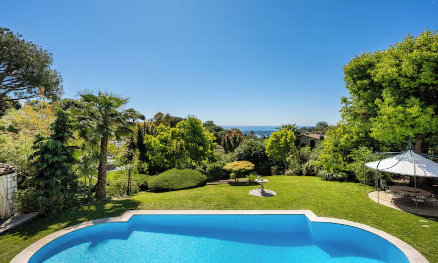A backyard with a swimming pool, surrounded by well-maintained lawns and trees.