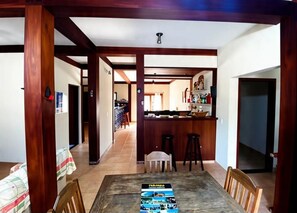 Un comedor con mesa, sillas y una barra al fondo.