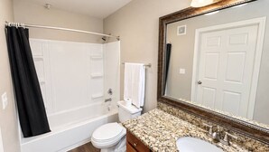 Ein Badezimmer mit Badewanne, Toilette, Waschbecken und einem großen Spiegel.