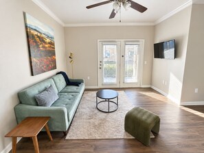 A living room with a sofa, a coffee table, and a television. - Sleepover | Cozy 1BD/1BA + Gym - Corpus Christi (Corpus Christi)