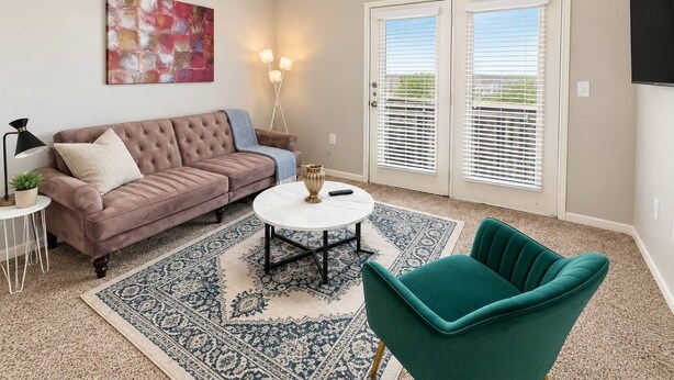 Un salon comprenant un canapé, une table basse, un fauteuil, un tableau et un ventilateur de plafond.
