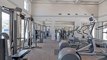 A gym with various exercise equipment, including treadmills and weight machines, arranged in a spacious layout.