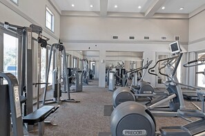 A gym with various exercise equipment, including treadmills and weight machines, arranged in a spacious layout.