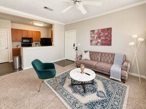 A living room with a sofa, a green chair, a coffee table, and a rug.