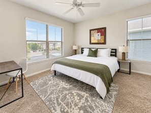 A bedroom with a bed, two bedside tables, a desk, and a chair. - Sleepover | Breezy 1BD/1BA + Gym - Corpus Christi (Corpus Christi)
