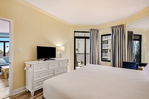 A hotel room with a large bed, a television on a dresser, and a balcony with a view. - Beach Colony 210 - Steps to the Beach (Myrtle Beach)