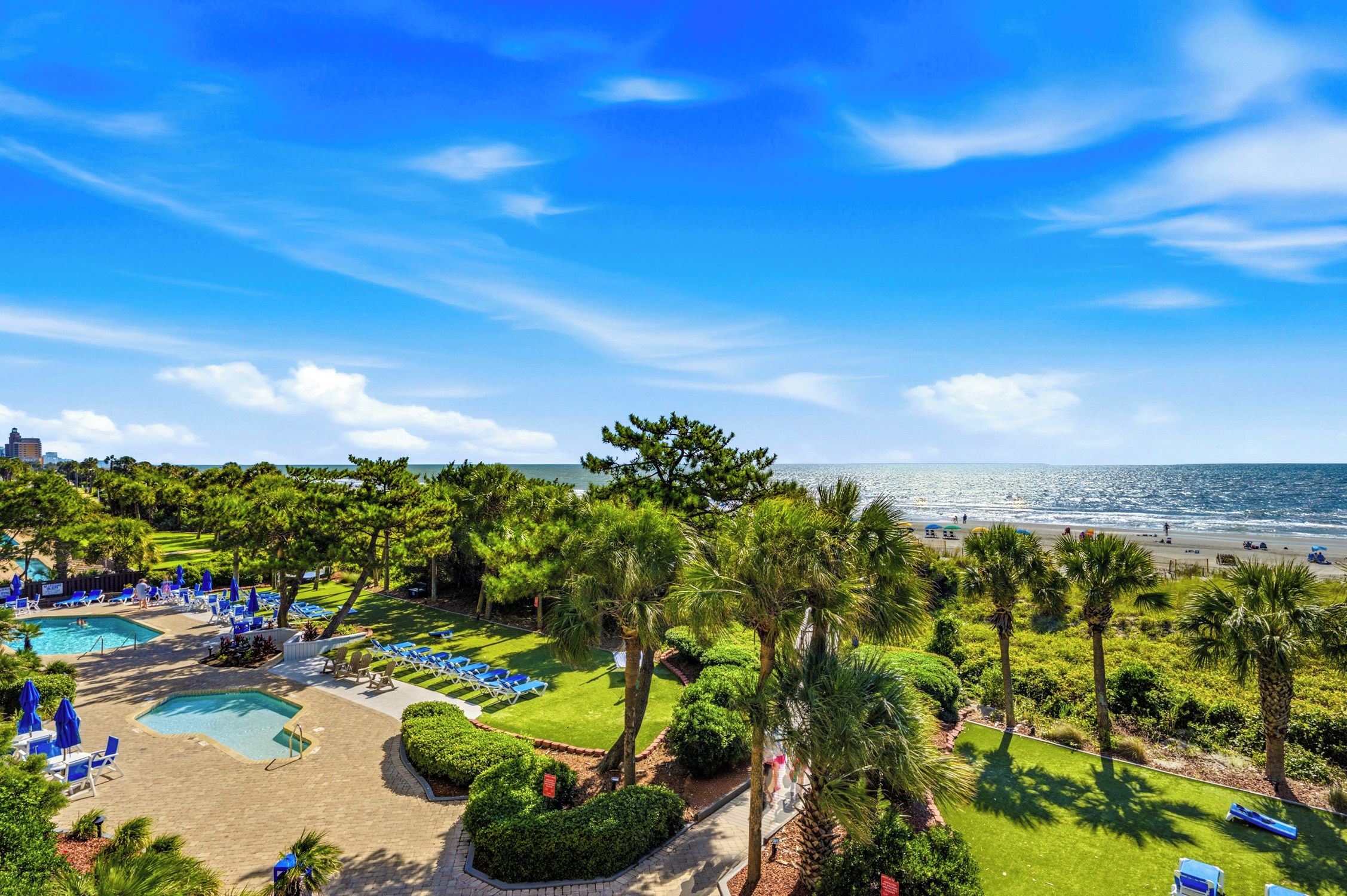 A resort with a swimming pool, beach, and ocean view.
