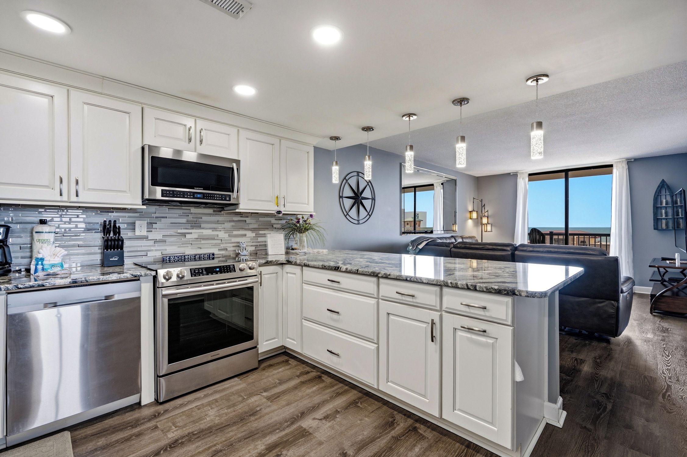A modern kitchen with stainless steel appliances, white cabinetry, and a large island.