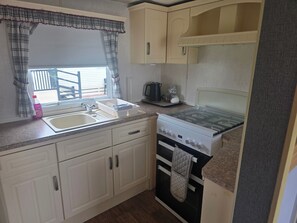 A compact kitchen with a sink, stove, and cabinets.