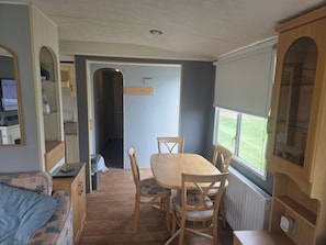 A compact living space with a dining area, kitchenette, and a view through a window. - 2-bed - Sleeps 6 - Free Parking (Arbroath)