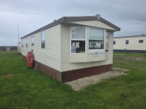 A mobile home with a front porch, a visible window, and a gas cylinder. - 2-bed - Sleeps 6 - Free Parking (Arbroath)