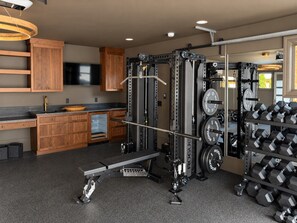 A home gym with a bench press, squat rack, and weight plates. - Maplewood Estate • Heated Pool, Hot Tub, Gym, Grill, Fire Pit (Nashville)