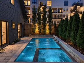 A rectangular swimming pool with a stone border, surrounded by a wooden deck and potted plants. - Maplewood Estate • Heated Pool, Hot Tub, Gym, Grill, Fire Pit (Nashville)