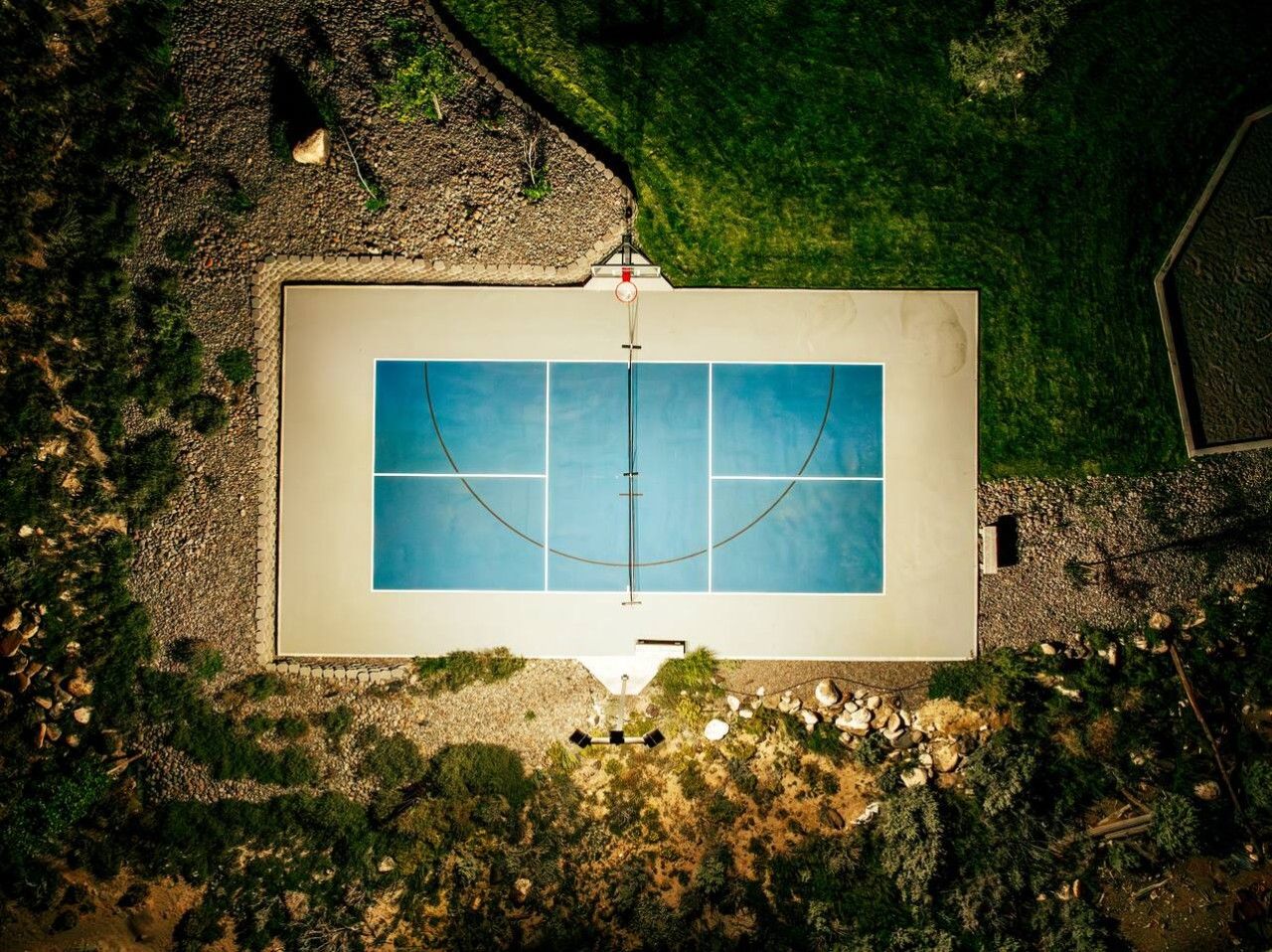 Luchtbeeld van een rechthoekig zwembad met een omliggend terras en een kleine tuin.