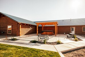 Eine Blockhütte mit überdachter Terrasse, einem Whirlpool und einem Grill.