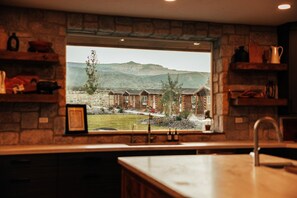 A kitchen with a stone wall and a window overlooking a mountain landscape.