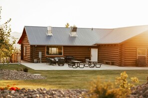 A log cabin with a patio area, outdoor seating, and a grill.