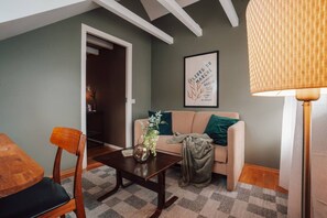 A cozy living room with a sofa, a coffee table, and a chair. There is a framed artwork on the wall and a lamp on the right. - Kaare’s Villa in Tromsø - Guest Favorite (Tromsø)