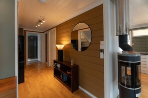 A hallway with wooden flooring, a round mirror on the wall, a small console table with decorative items, and a black heater on the right. - Kaare’s Villa in Tromsø - Guest Favorite (Tromsø)