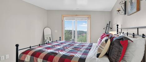 Un dormitorio con cama, ventana y lámpara de techo.
