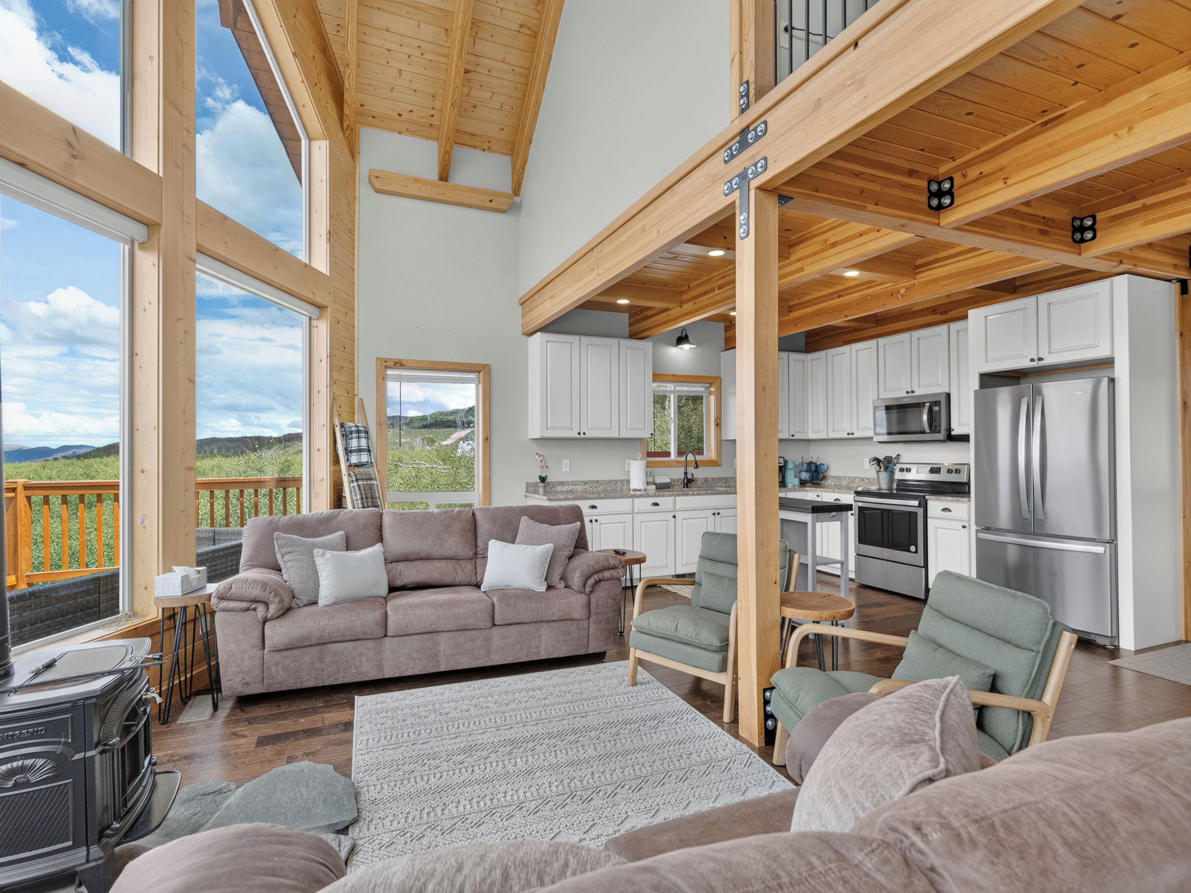 A spacious living area with a large window, a sofa, a dining table, and a kitchen with modern appliances.