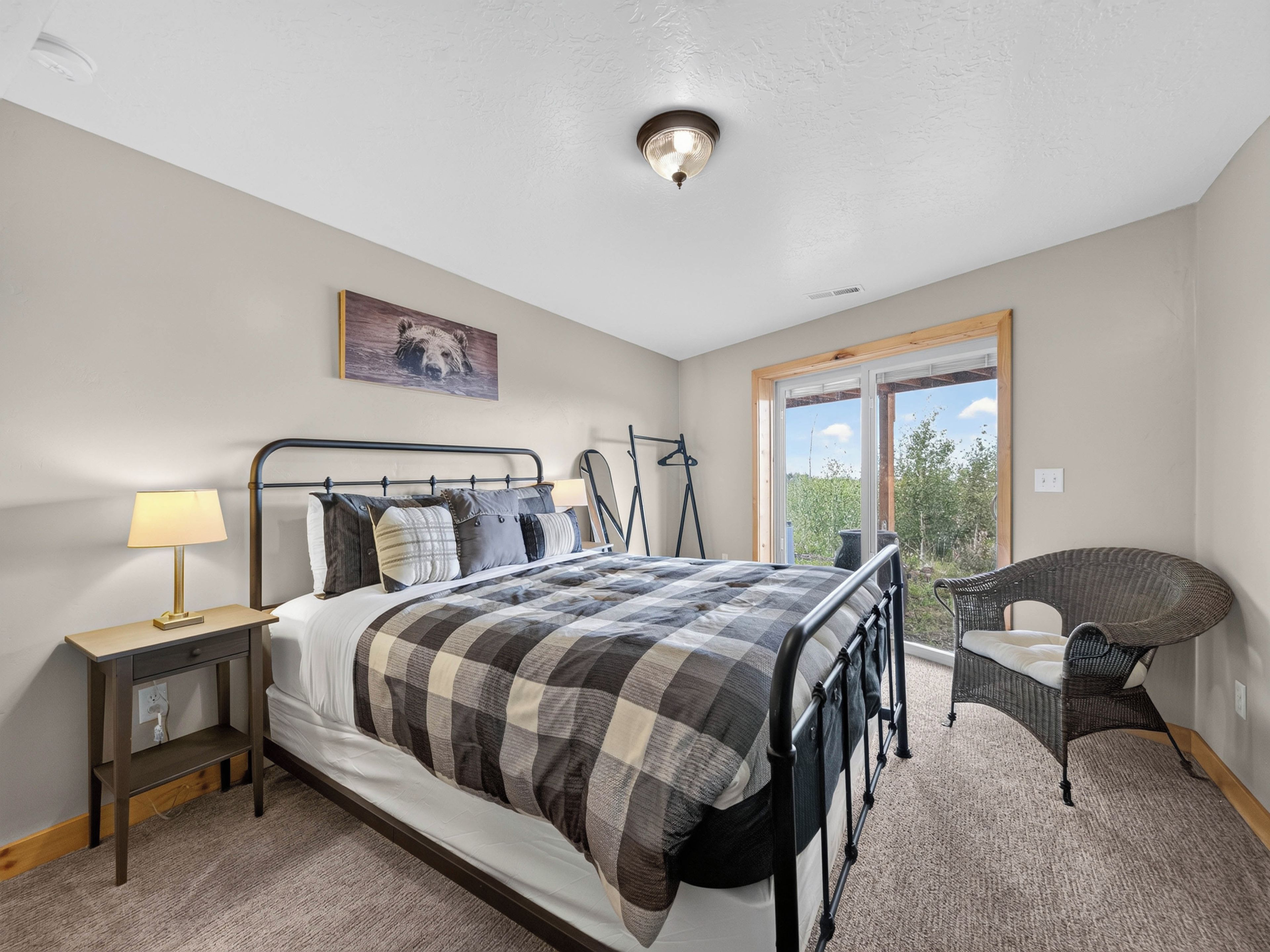 A bedroom with a bed, bedside table, lamp, and a chair.